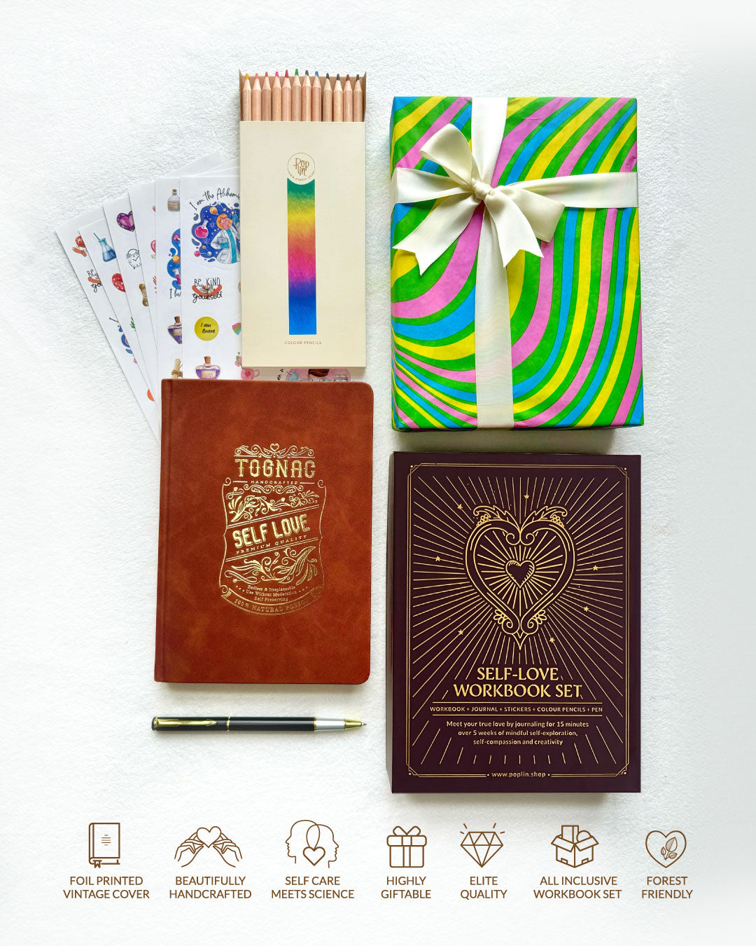 Set of self-love workbooks, a pen, and a colorful notebook with a bow on a white background.