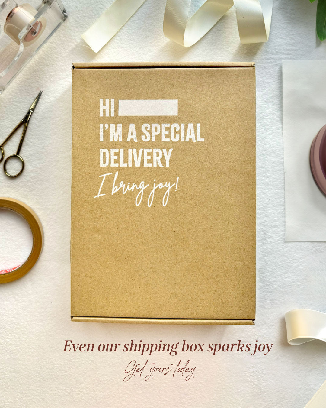 Kraft paper box with text 'Hi, I'm a special delivery. I bring joy!' on a white background with stationery items.